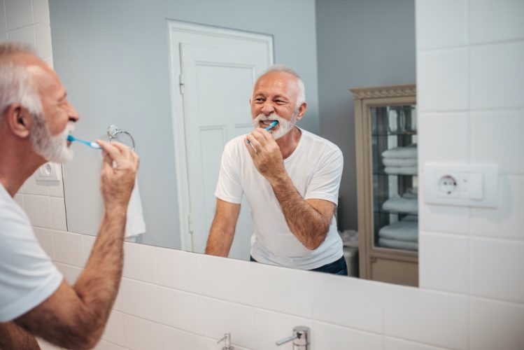 Shot of a mature man brushing his teeth in the bathroom